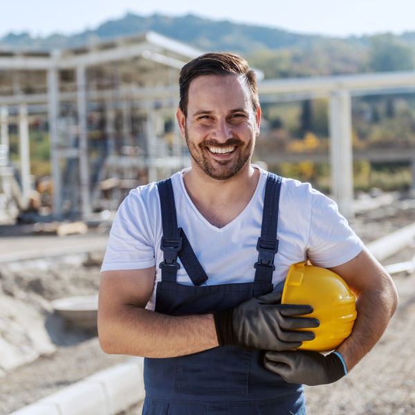construction worker holding helmet smiling